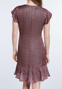Vestido floral con mangas cortas y volantes, cuerpo ajustado y dobladillo acampanado. Presenta un patrón de color rosa oscuro con pequeñas flores.