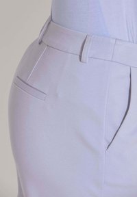 Helle Lavendel-Hosen mit glatter Textur, ausgestattet mit einem Bund, seitlichen Taschen und dezenten Falten für zusätzlichen Schwung.