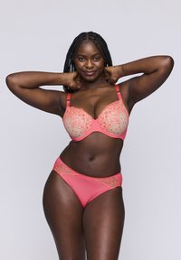 Korale i cielista koronkowa biustonosz z wyprofilowanymi miseczkami i regulowanymi ramiączkami, połączony z dopasowanymi koralowymi majtkami bikini z koronkowym wykończeniem.