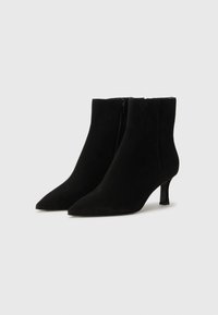 Bottines en daim noir avec un bout pointu, un design élégant et un talon bloc de hauteur moyenne. Fermeture éclair sur le côté. Texture lisse.