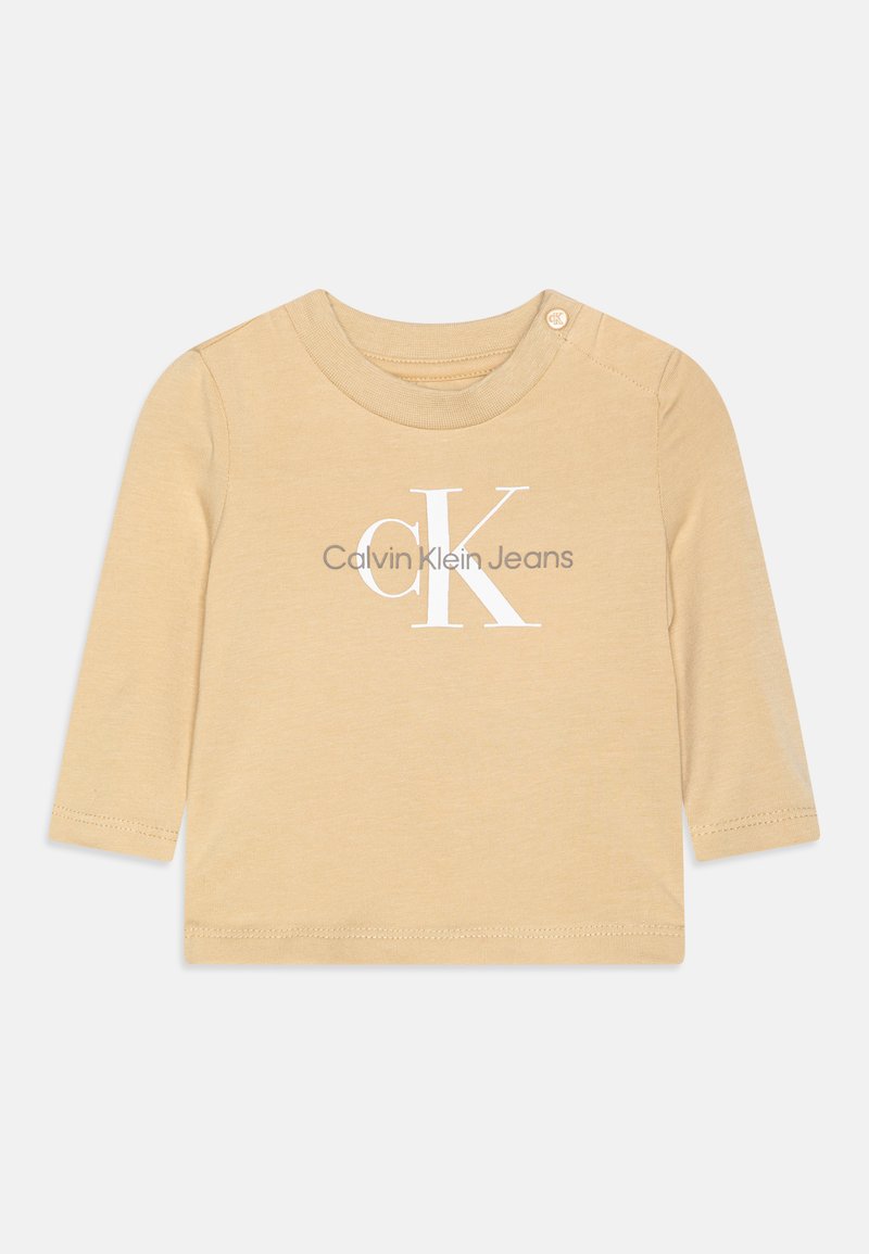 Bež majica dugih rukava od mekog pamuka, s bijelim tiskanim logotipom "Calvin Klein Jeans" i pritiskom na ramenu.