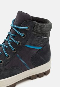 Botas de senderismo de color gris oscuro, hechas de ante y textil. Cuentan con cordones azules, costuras en contraste y una suela de goma para mayor tracción. Los acentos incluyen la marca.