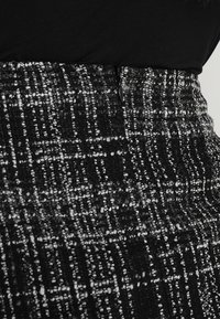Gonna tweed bianca e nera con un motivo testurizzato, design a vita alta e chiusura con zip laterale.
