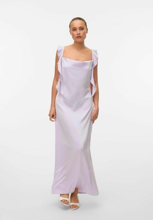 Robe longue lavande avec un décolleté carré, en tissu fluide, accents froncés sur les épaules et une silhouette lisse et élégante. Portée avec des talons blancs.