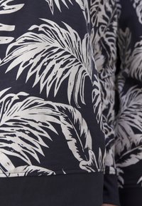 Sudadera azul marino con estampado de hojas de palma blancas, fabricada en suave algodón, con cuello redondo y dobladillos y puños acanalados.