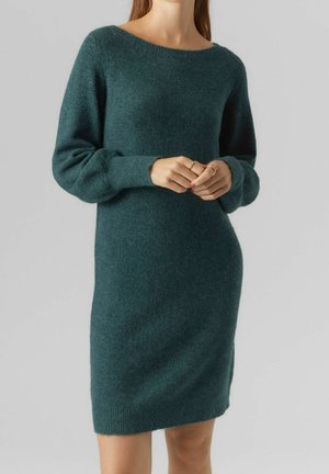 Vestito a maglia teal con maniche lunghe, scollatura ampia e silhouette aderente. La texture è morbida con polsini e orlo a coste.