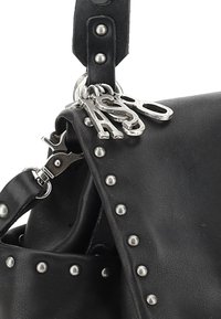 Sac à main en cuir noir avec des clous en métal le long du rabat, une surface texturée et des éléments en métal argenté avec des pendentifs décoratifs attachés.