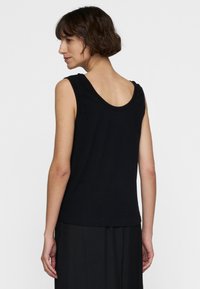 Zwarte mouwloze top met een ronde hals en een ontspannen pasvorm. Zacht materiaal met een gladde textuur, minimale naden en geen zichtbare patronen.