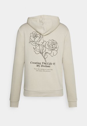 Sweat à capuche beige avec des roses dessinées en lignes noires dans le dos et le texte "Creating The Life Of My Dreams."