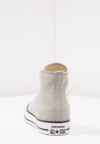 Grijze mesh hoge sneaker met een textuurafwerking, zwart-witte rubberen zool en een cirkelvormige logo patch op de achterkant.