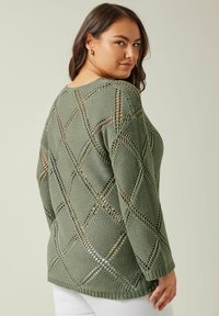 Sweter dziewiarski w stonowanej zieleni z diamentowym wzorem ażurowym. Posiada długie rękawy, ściągacz u dołu oraz fakturowany materiał. Lekki i przewiewny.