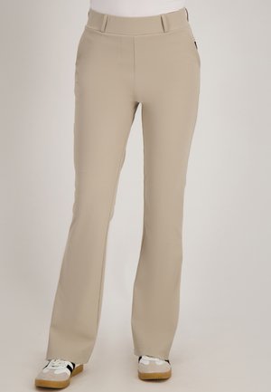 Beige rechte broek met steekzakken aan de voorkant, gecombineerd met witte en beige sneakers op een lichte achtergrond.