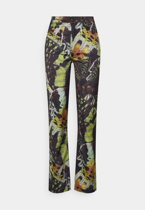 Smaltsiddende bukser med flerfarvede sommerfugle- og abstrakte mønstre i grøn, gul, orange og sort på en mørk baggrund.