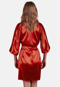 Accappatoio in raso rosso con una texture liscia, maniche a tre quarti, vita con cintura e design al ginocchio, visto da dietro.