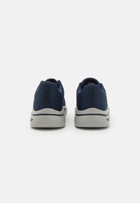 Scarpe da ginnastica blu navy con tomaia in mesh testurizzato e suola in gomma grigia, caratterizzate da un tassello per il tallone e un design elegante.