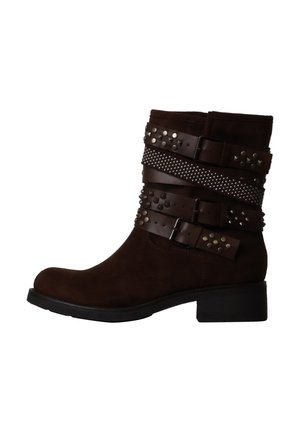 Bottine en daim marron foncé avec trois brides en cuir cloutées et un petit talon noir, vue de côté sur fond blanc.