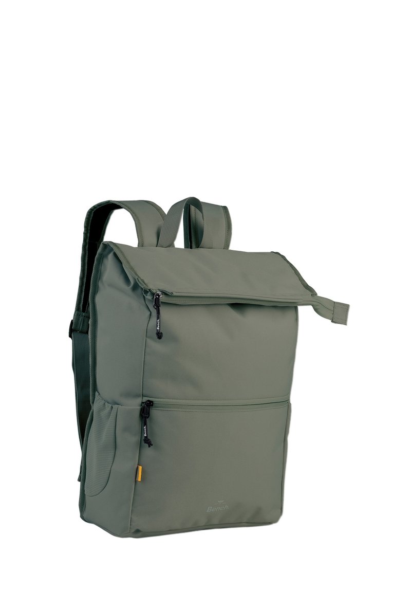 Sac à dos en tissu vert avec un rabat supérieur zippé, deux poches avant, des bretelles réglables et un détail de logo sur le panneau inférieur.