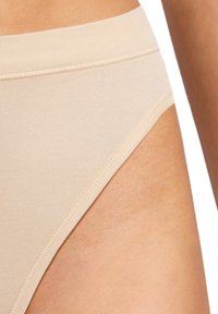 Mutande beige a vita alta realizzate in tessuto morbido, con cuciture lisce e un design minimalista, dotate di un'apertura per la gamba a taglio basso.