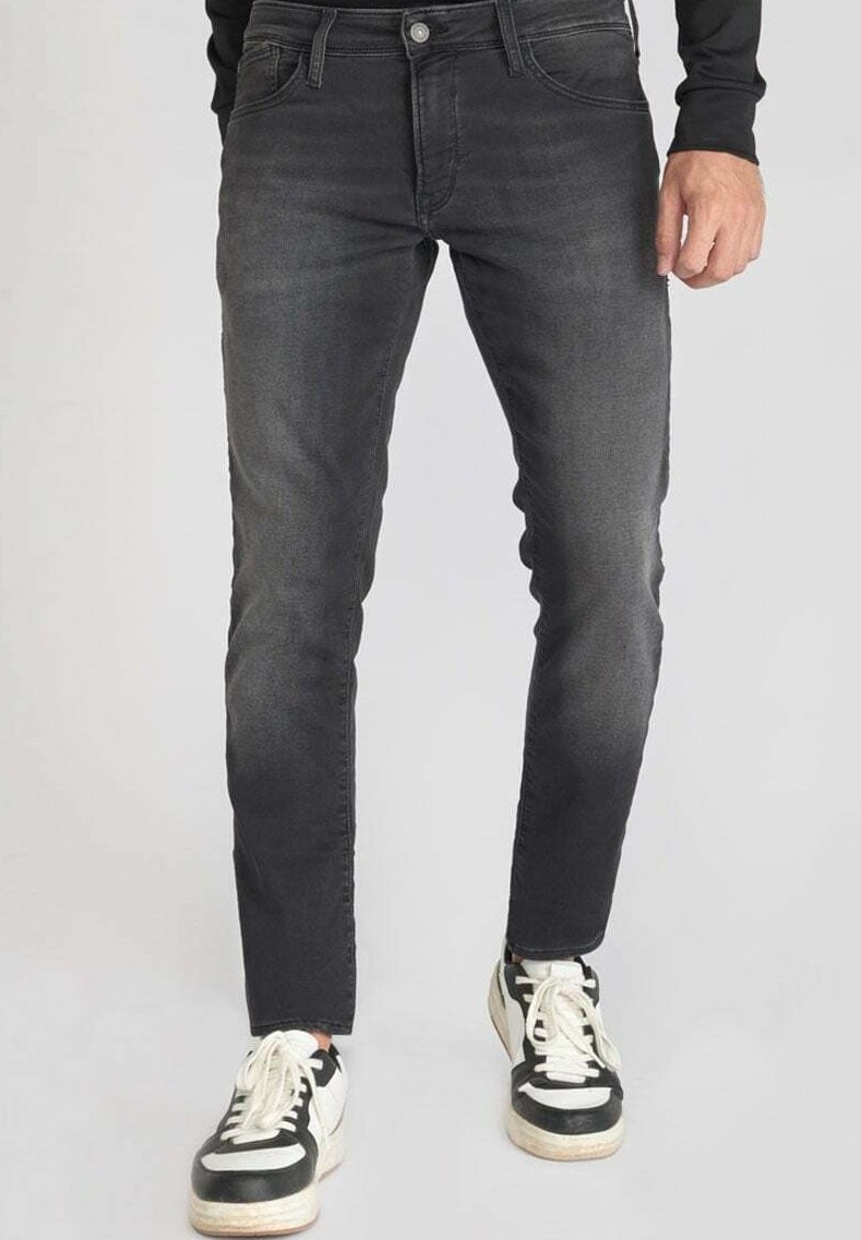 Jean noir slim en denim, avec un délavage naturel, un design à cinq poches et associés à des baskets noir et blanc.