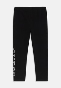 Leggings negre din bumbac elastic, cu un logo argintiu "GUESS" imprimat vertical pe piciorul stâng. Textură netedă, talie elastică.