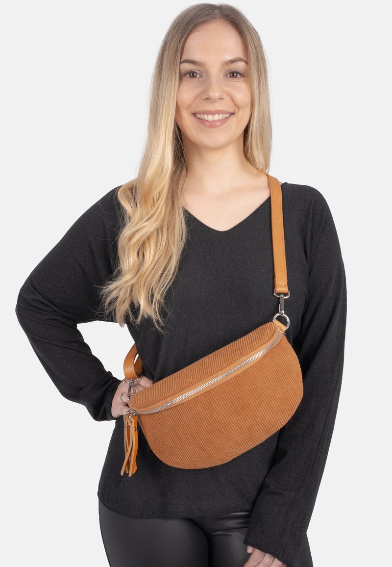 Braune Corduroy-Crossbody-Tasche mit geschwungener Form, Reißverschluss und abnehmbarem, hellbraunem Gurt. Mit strukturiertem Stoff und silbernen Hardware-Elementen.