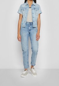 Ljusblå jeansjacka med korta ärmar, kombinerad med ljusblå högmidjade jeans och grå sneakers. Randig topp under.