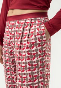 Rode longsleeve top in combinatie met gestreepte broek met rode, grijze en witte cirkelpatronen. Broek heeft zijzakken en plooien.