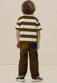 Gestreepte bruine en witte shirt met korte mouwen, gecombineerd met losse bruine broek met kleurrijke opbergzakken. Zachte textuur, casual pasvorm.