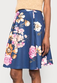 Blommig A-linje nederdel i marinblått tyg med rosa, orange och vita blommönster; plisserad design, mjuk textur och knälång fåll.