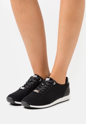 Baskets noires texturées avec bout rond, design à lacets et semelle blanche. Dotées d'accents argentés et d'un talon rembourré pour le confort.