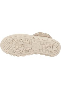 Suela de goma beige claro con una superficie texturizada que presenta un patrón de hojas y estrías para mayor tracción. Logo central en relieve.