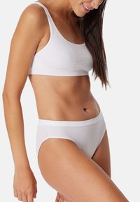 Bralette bianco a coste con spalline larghe e coordinati slip a vita alta. Texture morbida e design senza cuciture per il massimo comfort.
