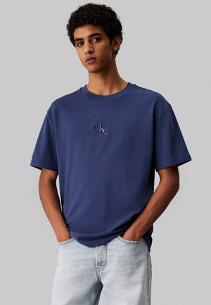 Camiseta de algodón azul marino de manga corta, con un logo bordado en el pecho. Textura suave y ajuste holgado.