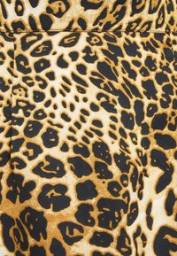 Tessuto con stampa leopardata che presenta un mix di grandi macchie nere e piccoli motivi marroni scuri su uno sfondo beige dorato. Texture liscia.