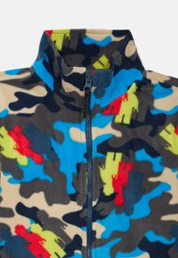 Fleece bunda s vystuženým golierom, so viacfarebným maskáčovým vzorom v modrej, červenej, zelenej a tmavosivej farbe, so zipsom v prednej časti.
