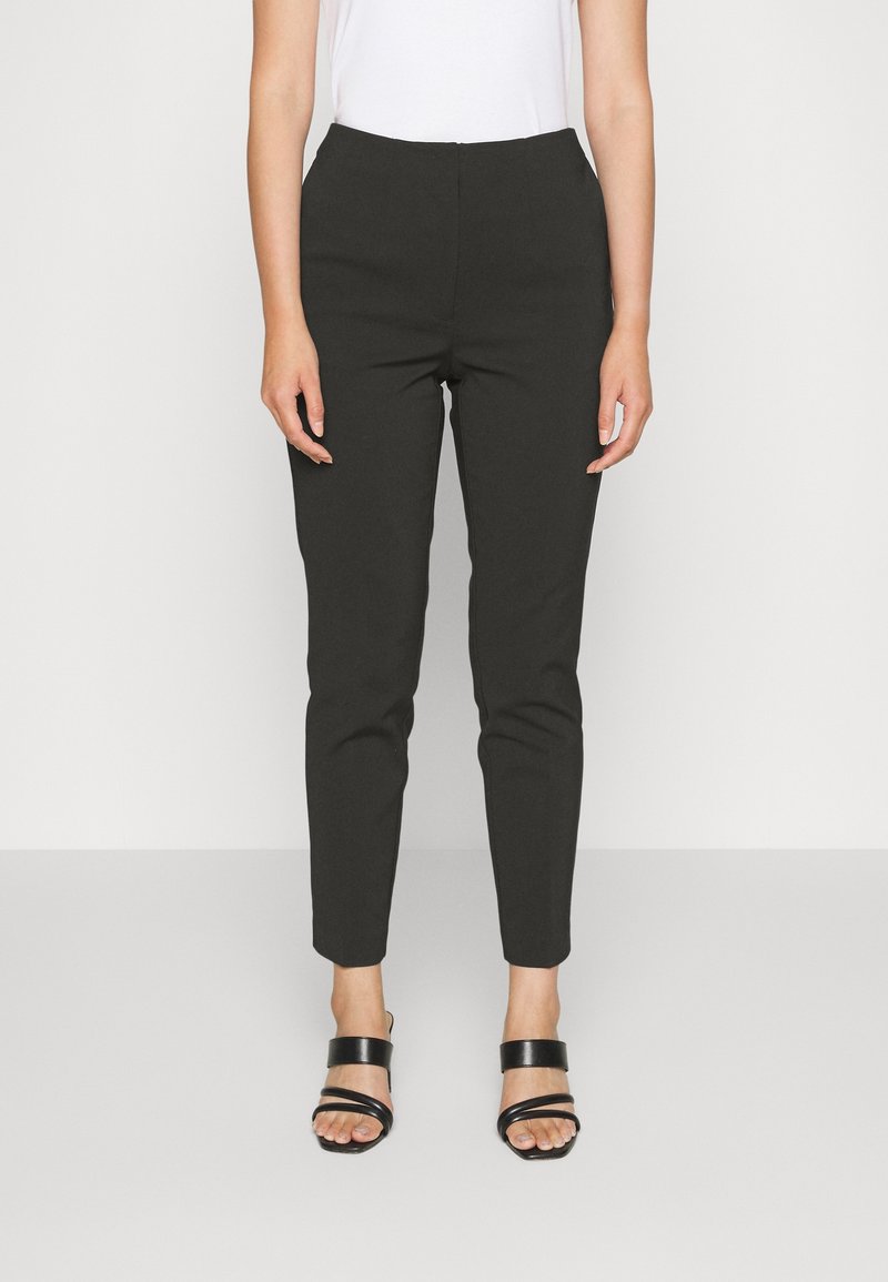 Černé tapered kalhoty s vysokým pasem, vyrobené z hladké látky. Přední kapsy, v kombinaci s černými páskovými sandály.