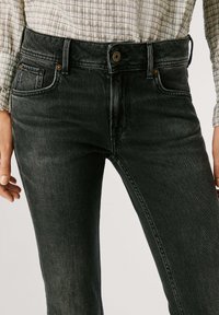 Čierne džíny z denimu s stredne vysokým pásom, jemným opotením a slim fit strihom. Obsahujú zlaté kovanie a klasický design s piatimi vreckami.