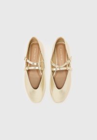 Ballerines métalliques dorées avec un bout pointu, un design à double bride et une texture lisse. Semelle flexible et semelle intérieure rembourrée.