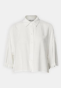 Chemise en lin blanc avec un col classique, des manches courtes et une fermeture à boutons sur le devant. Présente une coupe décontractée et un ourlet légèrement raccourci.