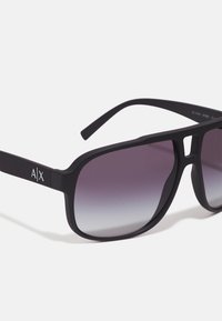Ochelari de soare negri în formă de pătrat, cu lentile gradient violet, având un finisaj mat și un accent cu logo pe braț.