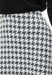 Tessuto a quadri houndstooth in bianco e nero con una texture morbida, completato da una parte superiore nera uniforme.