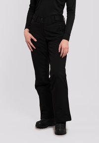 Schwarze Hosen aus strapazierfähigem Material, mit geradem Beinansatz, seitlichen Reißverschlüssen und einem Gürtel für eine verstellbare Passform. Die Schuhe sind ebenfalls schwarz.