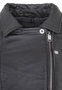 Schwarze Lederjacke mit spitzem Kragen, Reißverschluss mit silbernem Beschlag und glatter Textur. Nähte sind sichtbar.