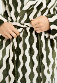 Blød badekåbe i mørkegrøn og hvid bølget mønster med bindebælte og blød tekstur, der fremhæver komfort og varme.