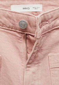 Jeans de mezclilla rosa claro con cierre de botón plateado y cremallera, con bolsillos laterales y tela texturizada. La etiqueta de la marca es visible.