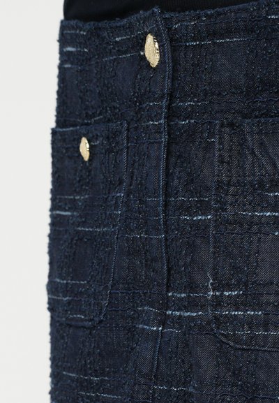 Jeans mini krilo v temno modri barvi z teksturirano tkanino, zlatimi gumbnimi detajli in dvema sprednjima žepoma. Ima šivani vzorec in raztrgan rob.