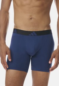 Mörkblå boxerkalsonger i stretchigt tyg med en svart midjeband som har en subtil blå logotyp och diagonala ränder.