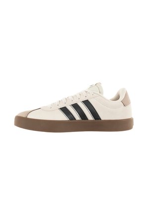 Zapato de ante beige con tres rayas negras, suela de goma marrón y diseño de cordones. Presenta una punta redondeada y un acento de talón en color tostado.
