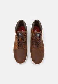Bruna lädersneakers av hög modell med en slät yta, rund tå, mörkbruna detaljer och bruna snörningar. Vit gummisula och logotyp.