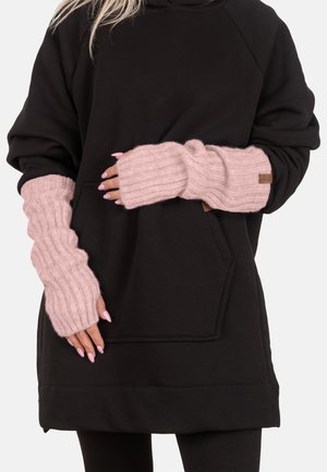 Femme portant un sweat-shirt noir ample et des gants sans doigts en tricot côtelé rose avec de longs ongles polis.